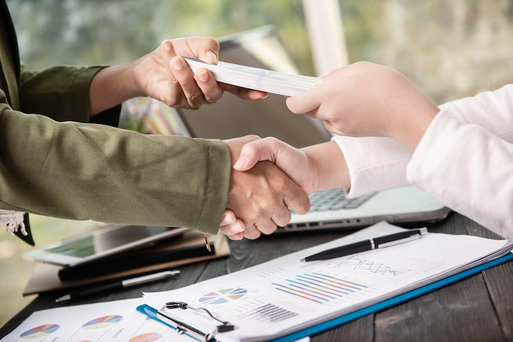 Handshake over financial charts, symbolizing business partnership and expansion in Vietnam.